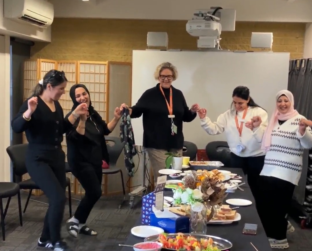 Five educators holding hands and dancing as they celebrate a team effort