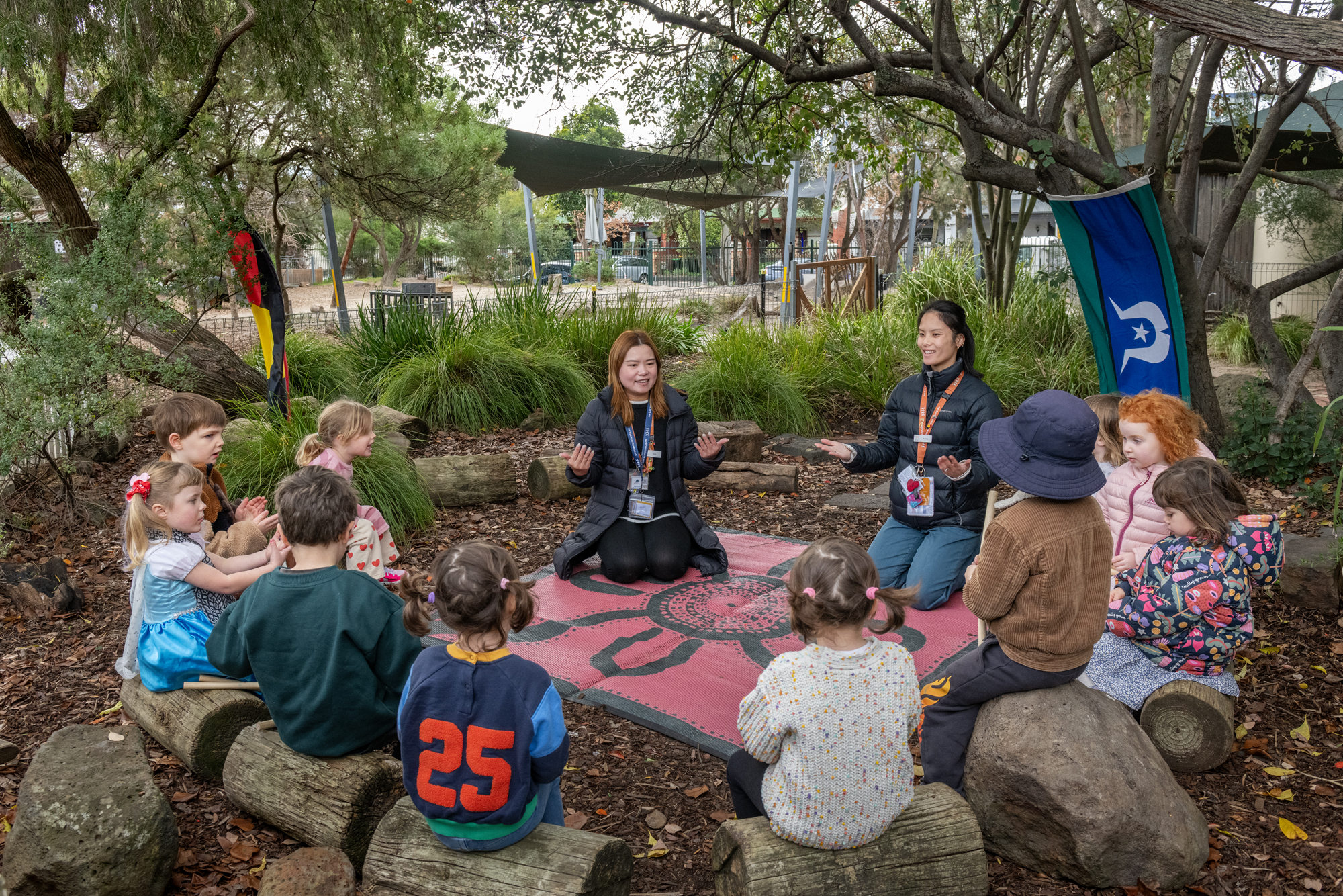 Children and educators gather in a circle outdoors to perform an Acknowledgement of Country.