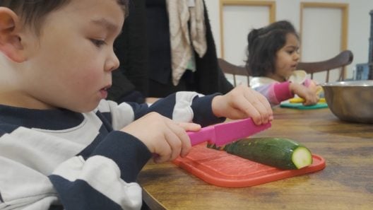 Child is cutting up vegetables with a child-friendly knife